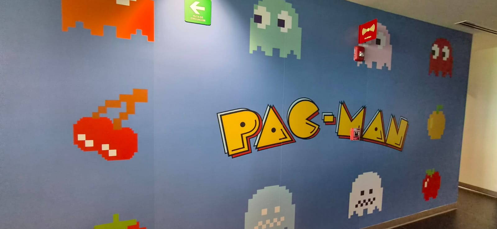 A Pac-Man mural with colorful pixel-art characters on a blue wall.