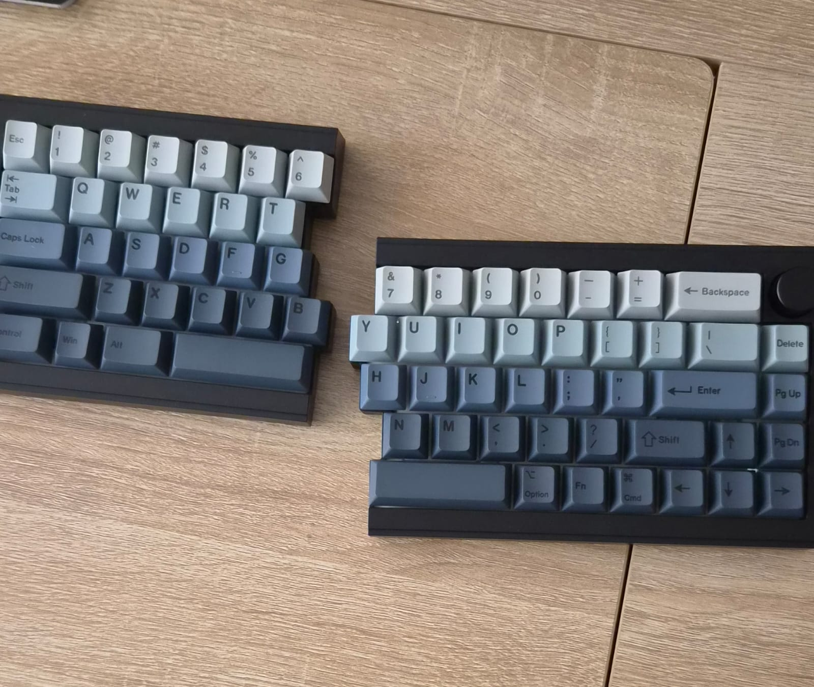 Two mechanical keyboards on a wooden desk.
